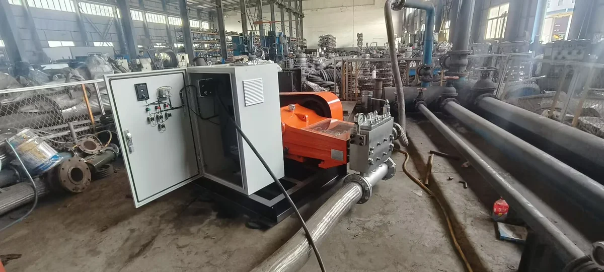 A plunger pump with its control cabinet and connected pipework in a workshop test arrangement
