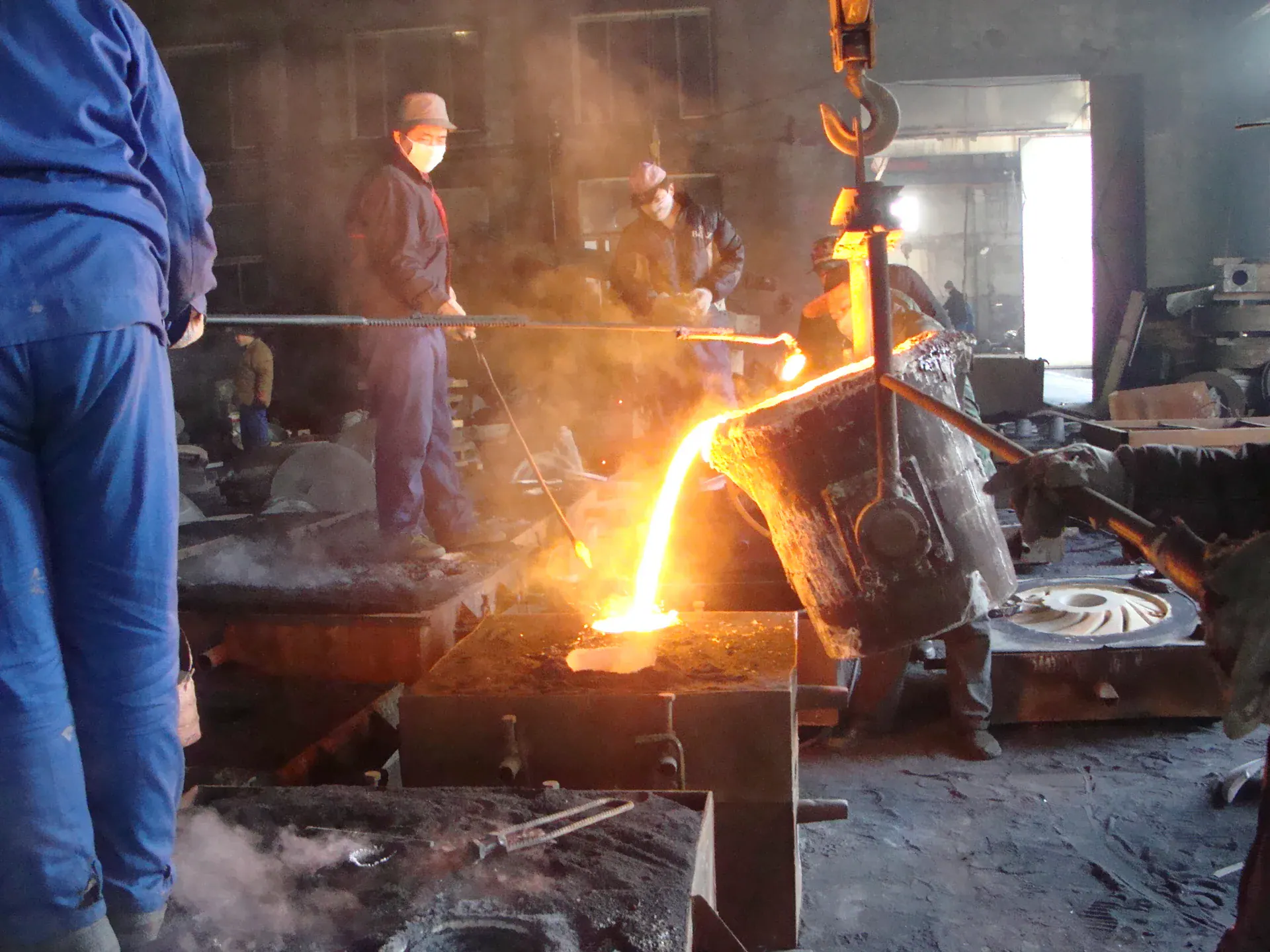 Foundry workers pouring molten metal into a pump-component mold