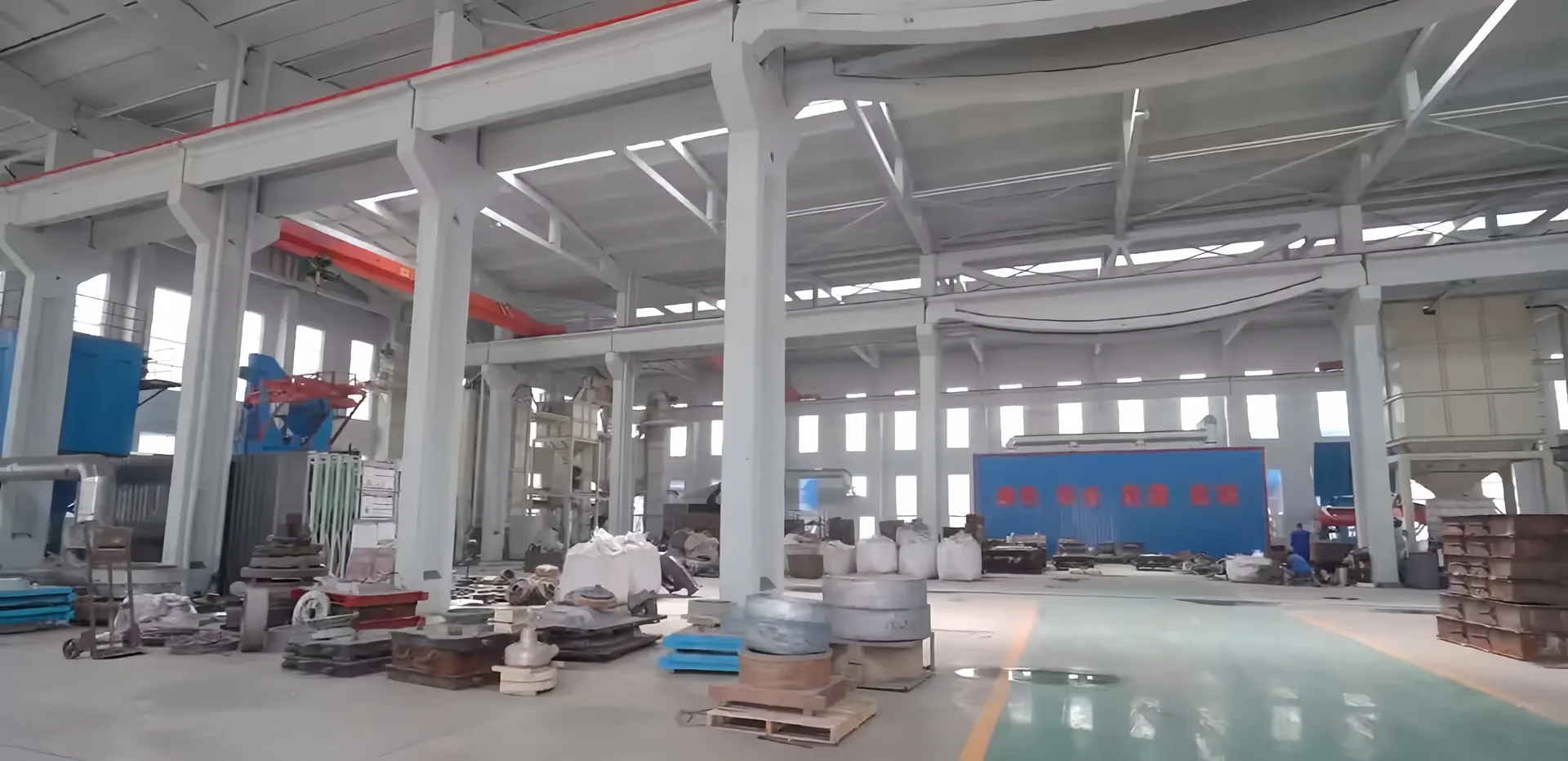 Pump manufacturing workshop with overhead cranes and components on the factory floor